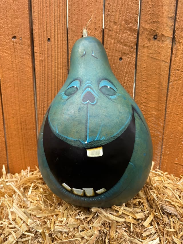 A cheerful blue hand-painted Gourdkin sitting in straw
